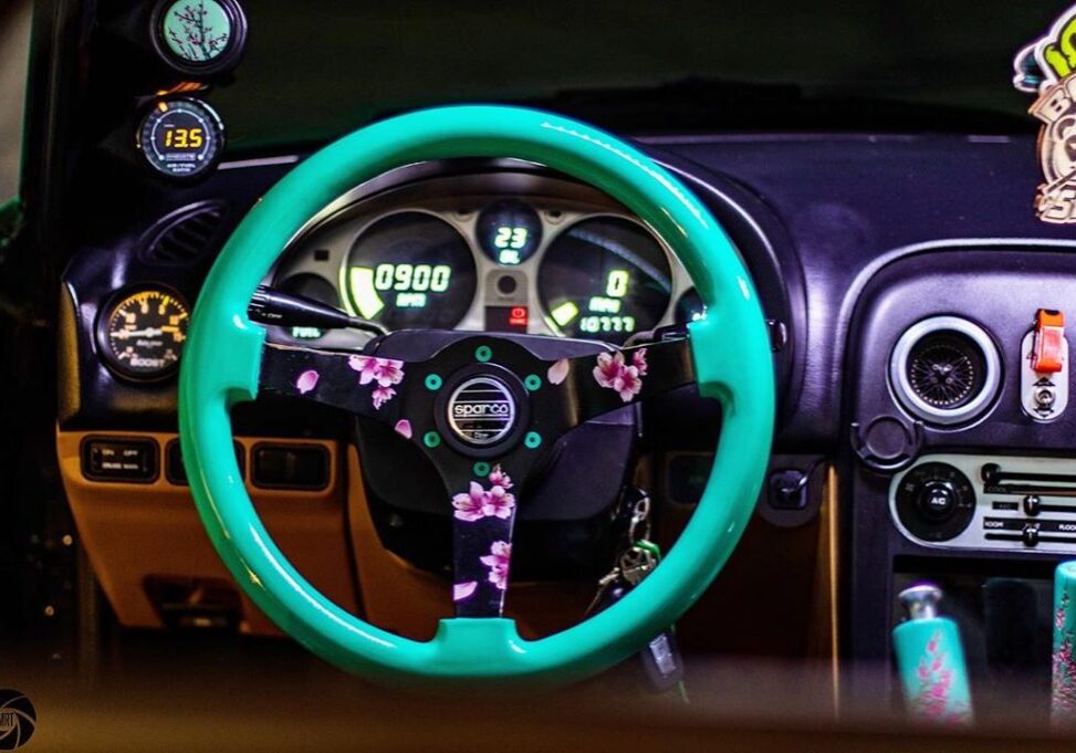 The inside of a car with a mint steering wheel and digital cluster